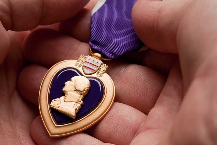 A hand holding a Purple Heart medal with a purple ribbon