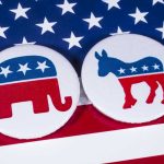 Republican elephant and Democrat donkey on American flag.