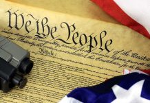 Close-up of the U.S. Constitution with a firearm and American flag