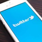 Close-up of a smartphone displaying the Twitter logo on a blue background