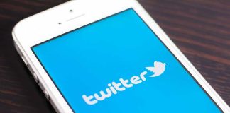 Close-up of a smartphone displaying the Twitter logo on a blue background