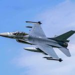 Jet fighter flying through clear blue sky.