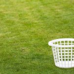An empty white laundry basket placed on green grass