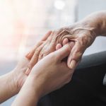 Alzheimer’s Crisis Every 65 Seconds — Shocking Surge Young hands holding an elderly persons hand.