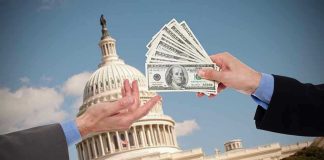 Hands exchanging money in front of Capitol building.