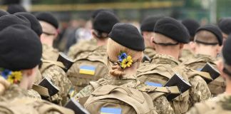 Soldiers in camouflage uniforms with Ukrainian flags.