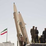 May 4 Incident: Hormuz on Razor’s Edge Military personnel beside missiles and Iranian flag.