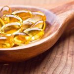 How Fat Actually Burns – 60 Years of Lies Golden omega-3 capsules in a wooden spoon