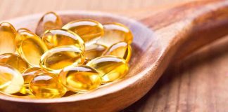 Golden omega-3 capsules in a wooden spoon