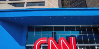 Exterior view of the CNN building with a large red logo and blue facade