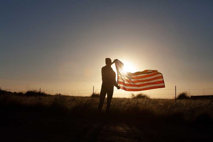 shutterstock_220513060 Silhouette of a person holding an American flag against a sunset