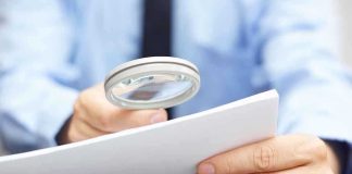 A person using a magnifying glass to examine a document closely