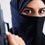 A woman in a black hijab holding a gun with an intense gaze