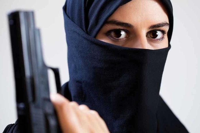 A woman in a black hijab holding a gun with an intense gaze