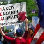 Protesters holding signs against taxation at a political demonstration