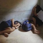 Three people huddled in a dimly lit corner.