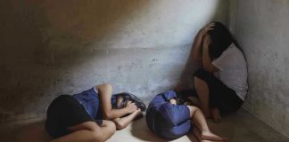 Three people huddled in a dimly lit corner.