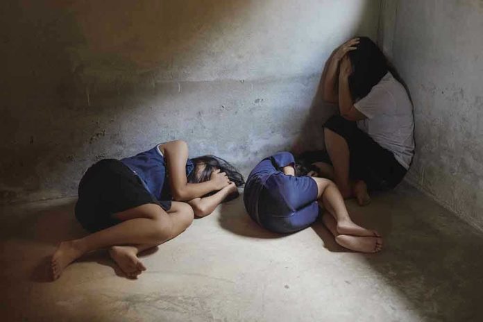 Three people huddled in a dimly lit corner.