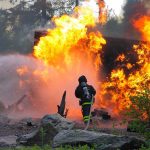 Wildfire Explodes—Officials Blame Humans Firefighter battling a large fire with water spray