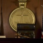 Title IX Showdown Ignites A judges bench in a courtroom with a gavel and flags
