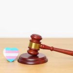 A wooden gavel next to a heart-shaped transgender pride flag