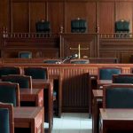 Supreme Showdown: Phones, Pleas, And Power Empty courtroom with wooden furnishings and judges bench.