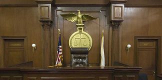 Judges bench in an empty courtroom, scales emblem above.