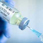 Pandemic Cash Pipeline — Minnesota To Mogadishu Gloved hand holding COVID19 vaccine vial and syringe