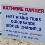 The Truth About UK Beach Risks Sign warning of tides, quicksand, hidden channels.