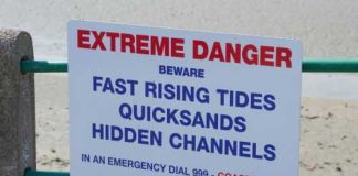 Sign warning of tides, quicksand, hidden channels.