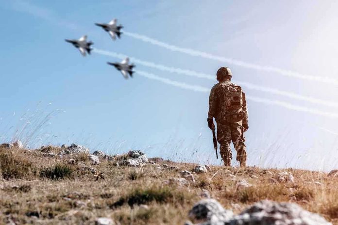 shutterstock_1689239632 Soldier standing on rocky hillside watching fighter jets fly overhead