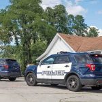 Two police SUVs parked near a suburban house