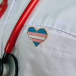 Heart-shaped pin on a white lab coat with red stethoscope