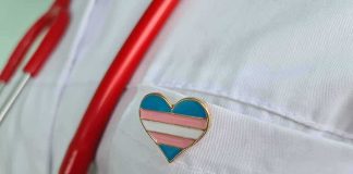 Heart-shaped pin on a white lab coat with red stethoscope