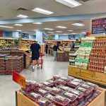 Price Tsunami Cracks Middle America Interior of a grocery store with customers shopping for fresh produce