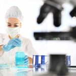 Scientist in lab coat handling blue liquid