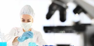 Scientist in lab coat handling blue liquid
