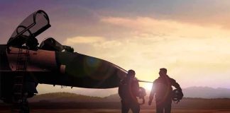 Two pilots walking beside a fighter jet at sunset