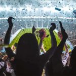 Fans cheering in a packed stadium during a night game