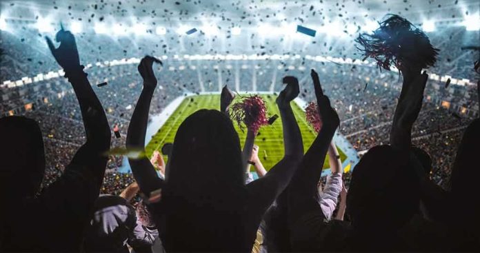 shutterstock_717281428 Fans cheering in a packed stadium during a night game