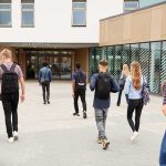 Students with backpacks walking toward a school entrance