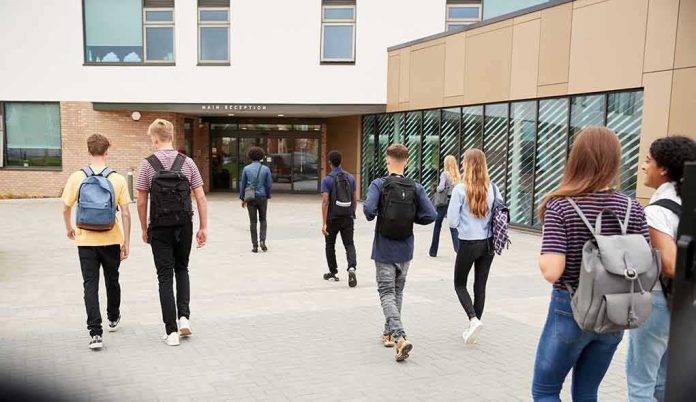shutterstock_1188882382 Students with backpacks walking toward a school entrance