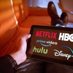 Person holding a tablet showing streaming service logos