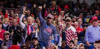 Crowd of supporters cheering at an indoor political rally