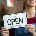 Shop worker holding an open sign