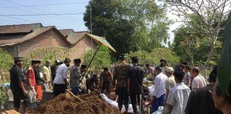 Mourners gather around a fresh grave during a burial ceremony