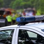 Police car with blue light bar at roadside scene