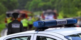 Police car with blue light bar at roadside scene