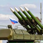Surface-to-air missile launcher with green rockets and a raised Russian flag