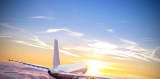 Airplane flying above clouds at sunrise